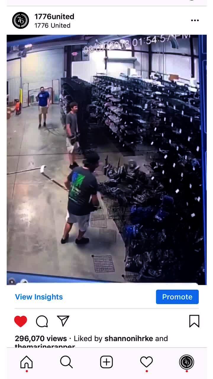 Video thumbnail showing: Three men play hockey at work, in a large storage room. One man bends over to pick up the hockey puck, and leans against a clothing rack. The rack falls over, and knocks down the other rack behind it too. Secondary source, screen recording from Instagram.