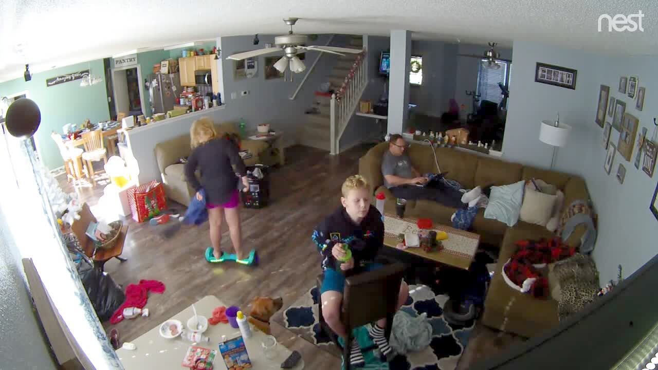 Video thumbnail showing: A teen girl puts on her sweatshirt while she rides a hover board and runs into  a wall  and falls on the ground. Security footage.